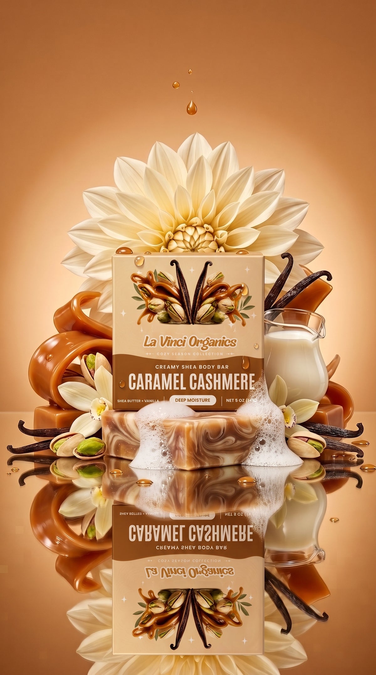 A boxed bar of soap labeled 'La Vinci Organics Caramel Cashmere' is centered on a warm brown studio background, surrounded by decorative elements including a large cream flower, vanilla beans, caramel pieces, a small glass of milk, and soap foam. The product box is the main subject, and the scene is styled as a clean commercial product shot.
